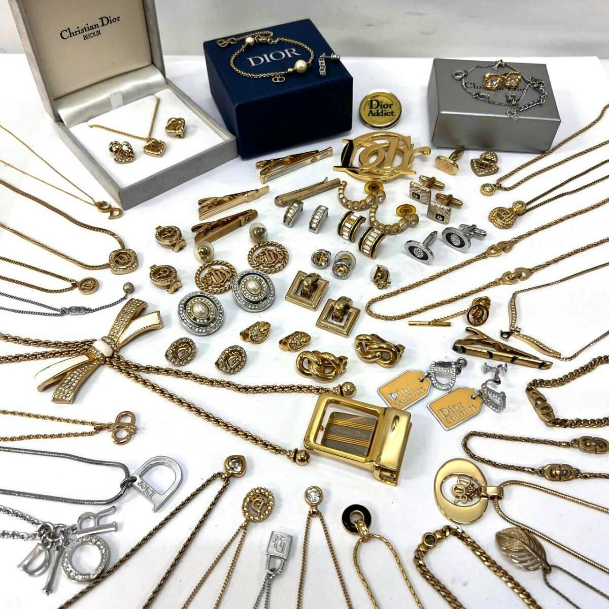 Photo of assorted Christian Dior necklaces and other Dior jewelry pieces (earrings, charms, brooches) laid out on a white surface.