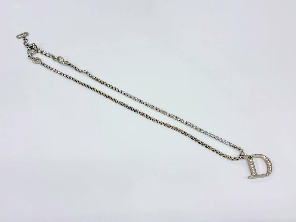 Silver-color Christian Dior necklace laid flat on a white background, showing a rhinestone-studded D logo pendant.