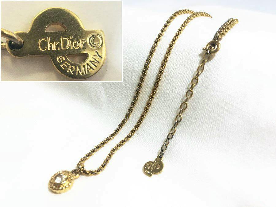 Gold-colored Christian Dior chain necklace with a small rhinestone pendant and a round "Chr. Dior GERMANY" tag on a white background.