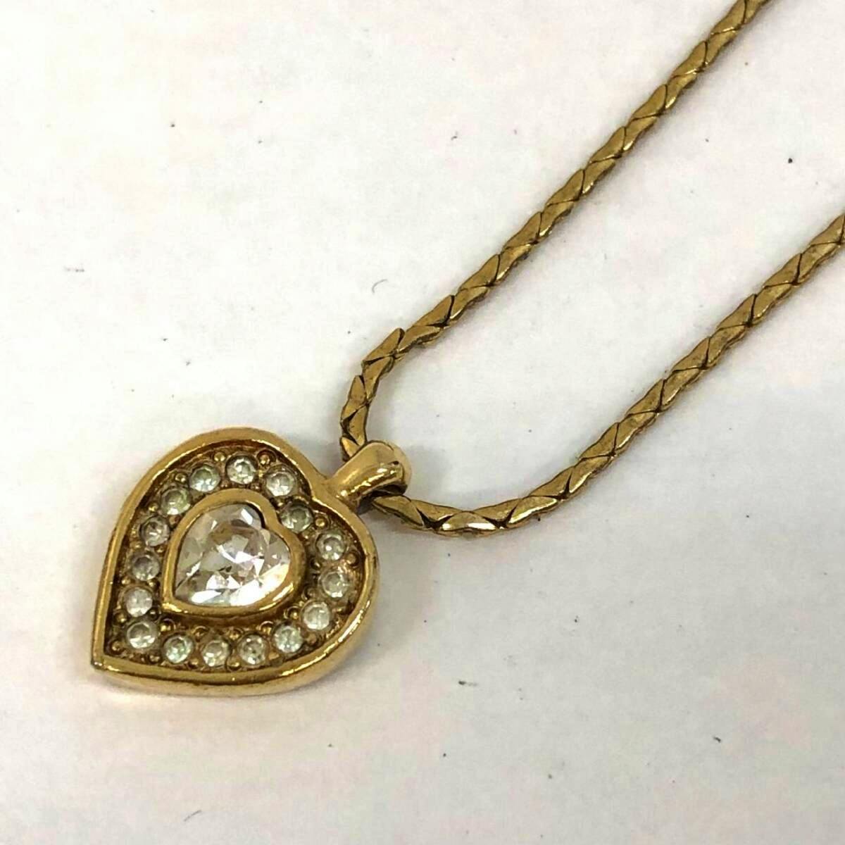 Gold-tone heart pendant with a central clear rhinestone and a ring of smaller rhinestones shown on a gold chain against a white background.