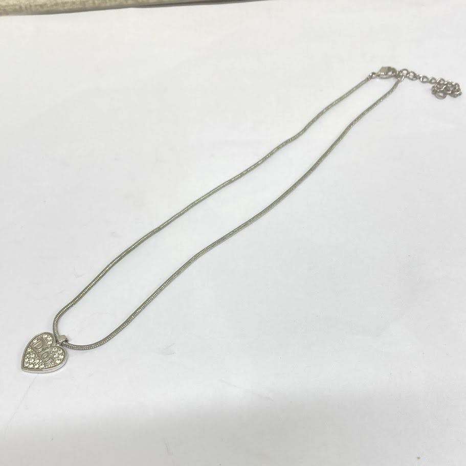 Silver-colored heart pendant necklace with rhinestones on a double snake-style chain laid flat on a white background.