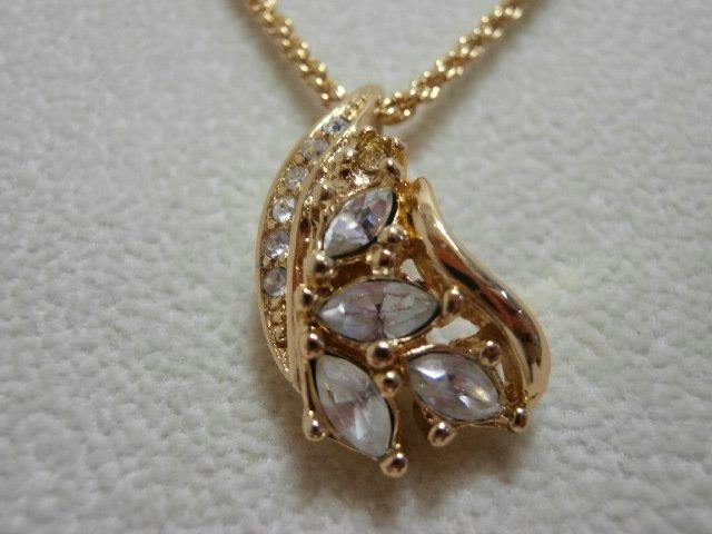 Close-up of the Christian Dior gold-tone necklace pendant decorated with clear rhinestone stones on a chain.