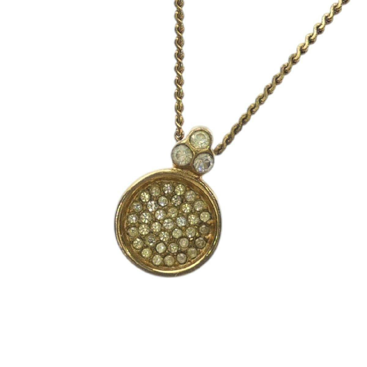Close-up of a Christian Dior gold-colored necklace pendant set with multiple small rhinestones and three stones at the bail on a white background.