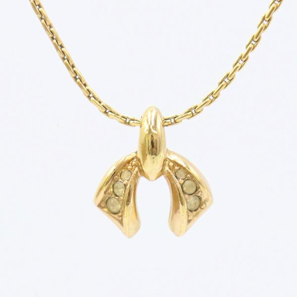 Close-up of a gold-tone Christian Dior ribbon-motif necklace pendant with rhinestones on a chain.
