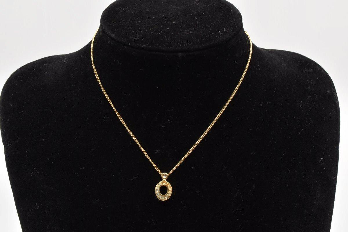 Gold-tone Christian Dior necklace with a round rhinestone pendant displayed on a black velvet bust.