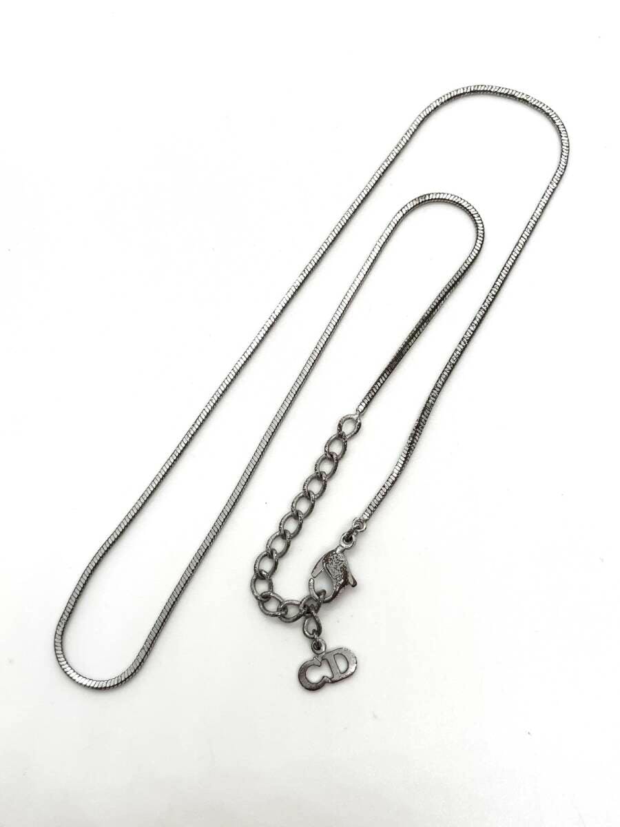 Silver-color Christian Dior women's necklace chain with extension and small 'CD' charm laid flat on a white background.