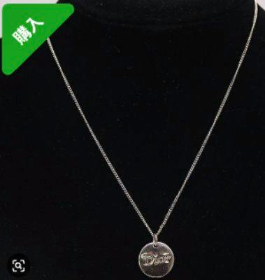 Silver-color Christian Dior necklace with a round logo plate pendant shown on a black display bust.