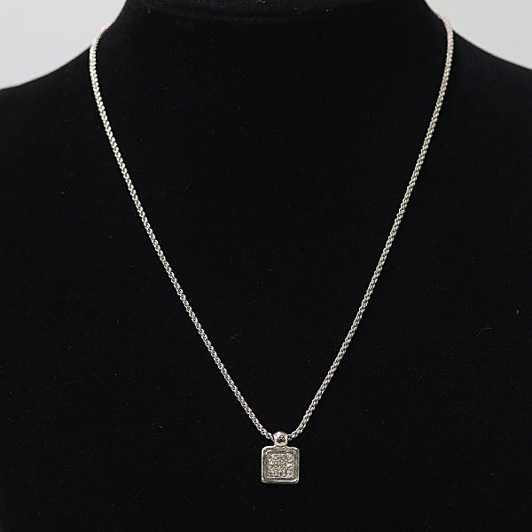 Silver necklace with a small square pendant displayed on a black mannequin bust.