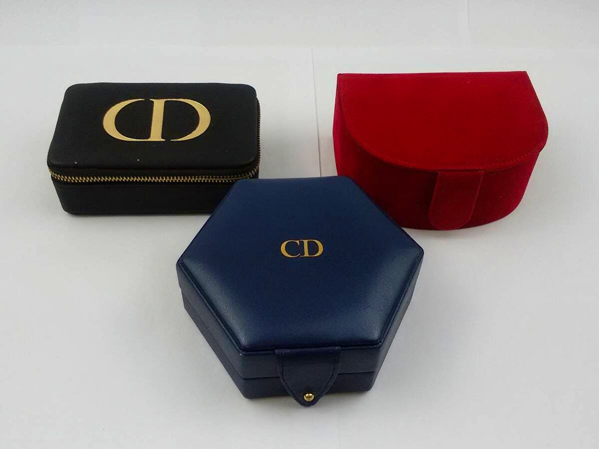 Three Christian Dior jewelry/accessory cases (black, red, and blue) displayed on a white background.