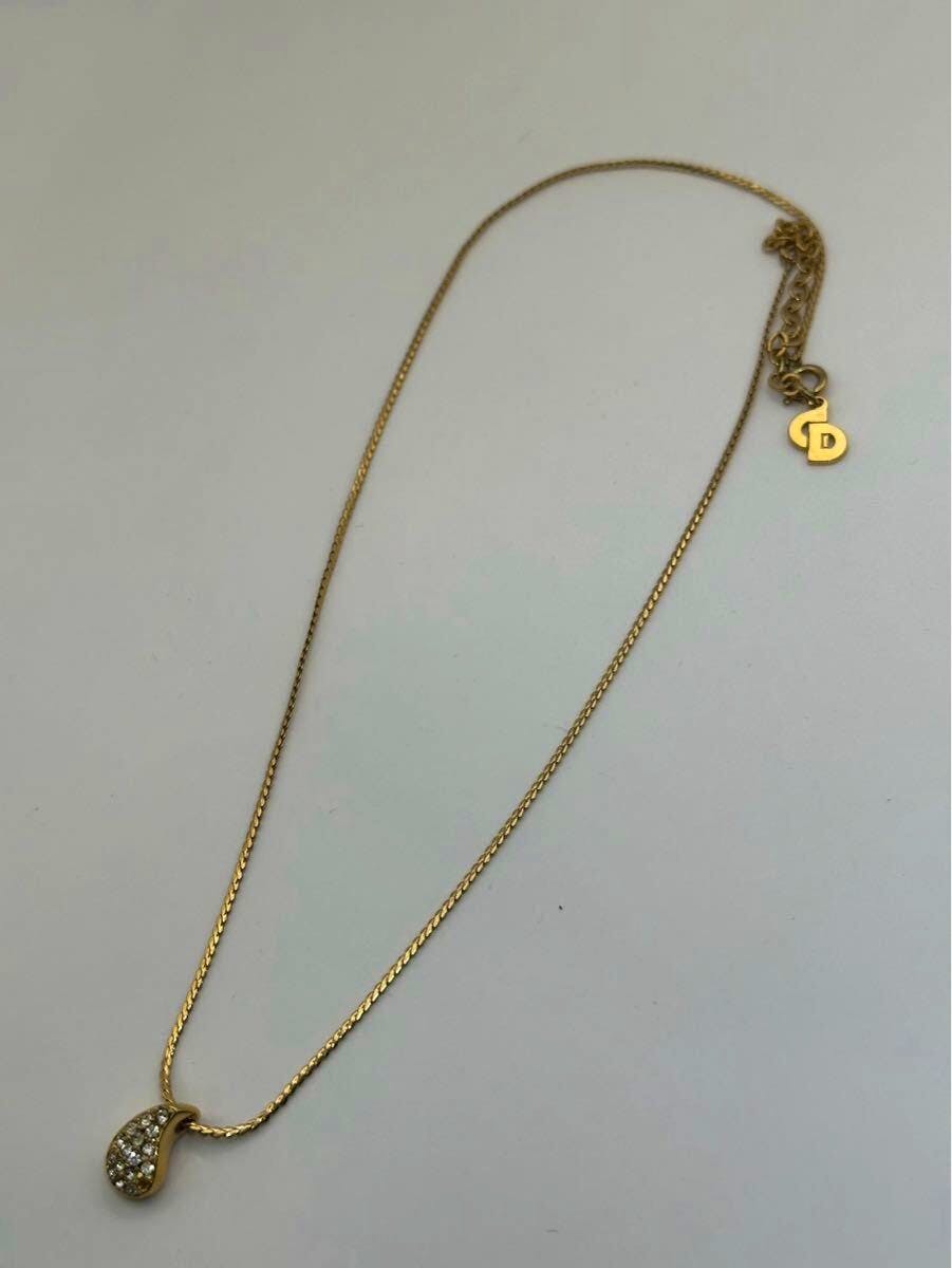 Gold-colored plated Christian Dior necklace laid flat showing a drop-shaped rhinestone pendant and chain.