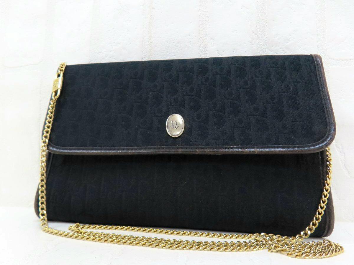 Black Christian Dior shoulder bag with trotter monogram fabric, a flap with round gold logo clasp, and a gold chain strap.