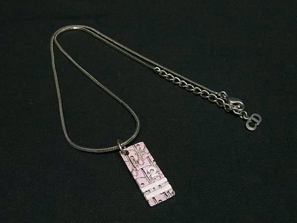 A Christian Dior silver-toned necklace with a pink patterned rectangular pendant on a thin chain against a black background.