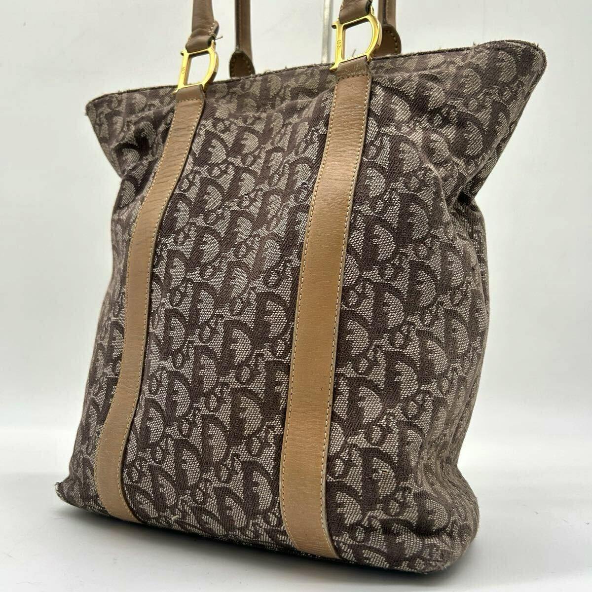 Front view of a Christian Dior canvas tote bag in beige Oblique monogram with tan leather vertical straps and gold D-shaped hardware.