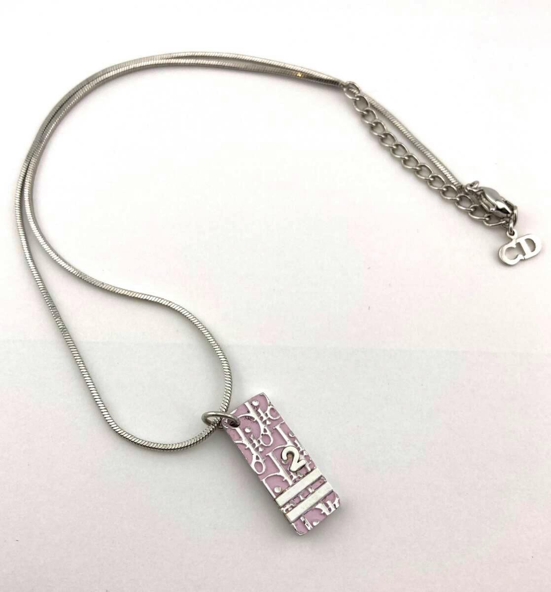 Silver-tone necklace with a pink rectangular Dior trotter plate pendant and a small CD charm laid on a white background.