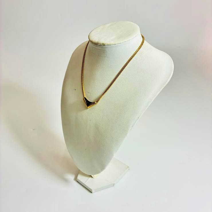 Gold-tone Christian Dior V-shaped triangle black pendant necklace displayed on a white bust.