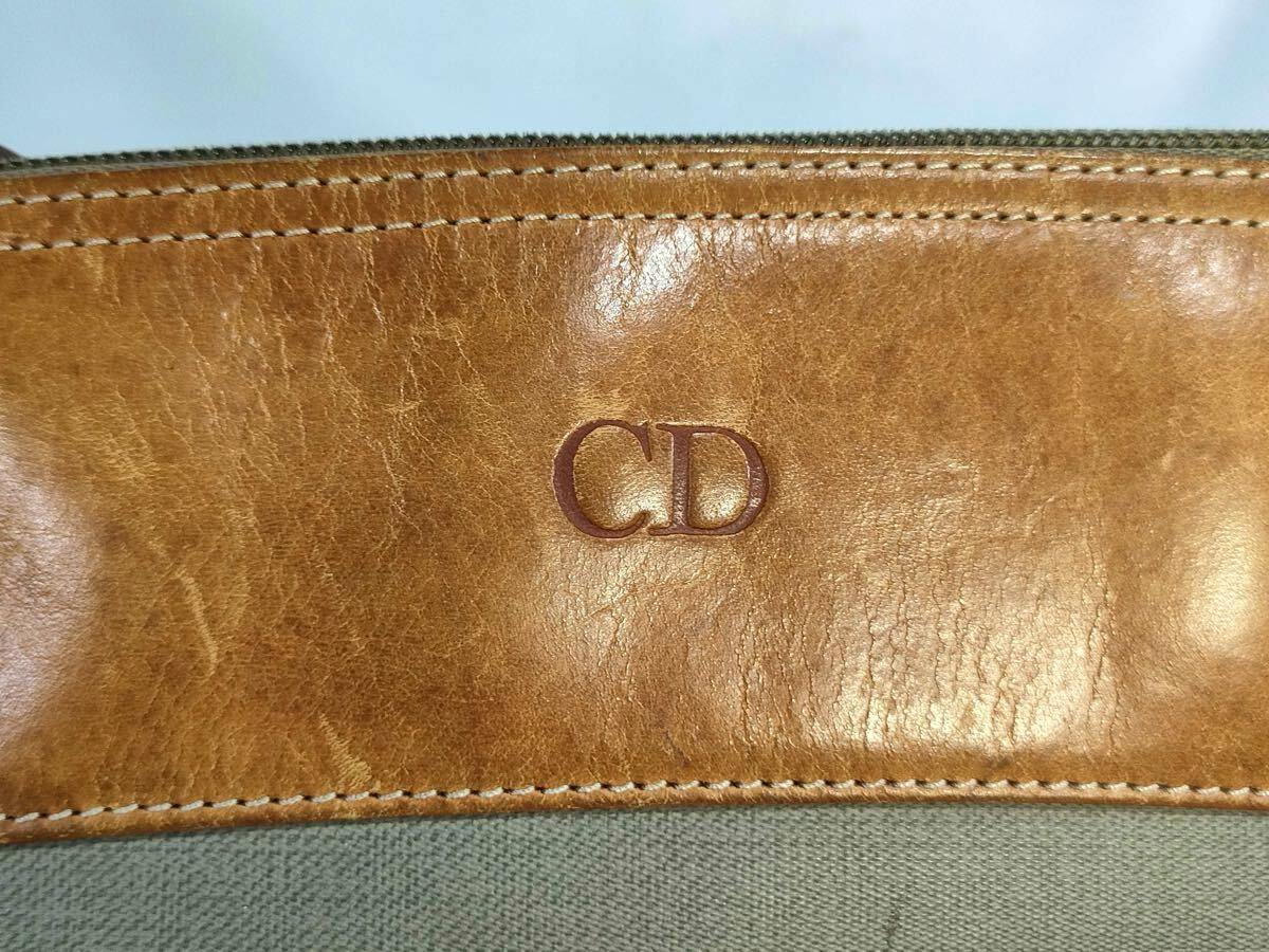 Close-up of the bag's leather trim showing an embossed "CD" logo above the canvas body.