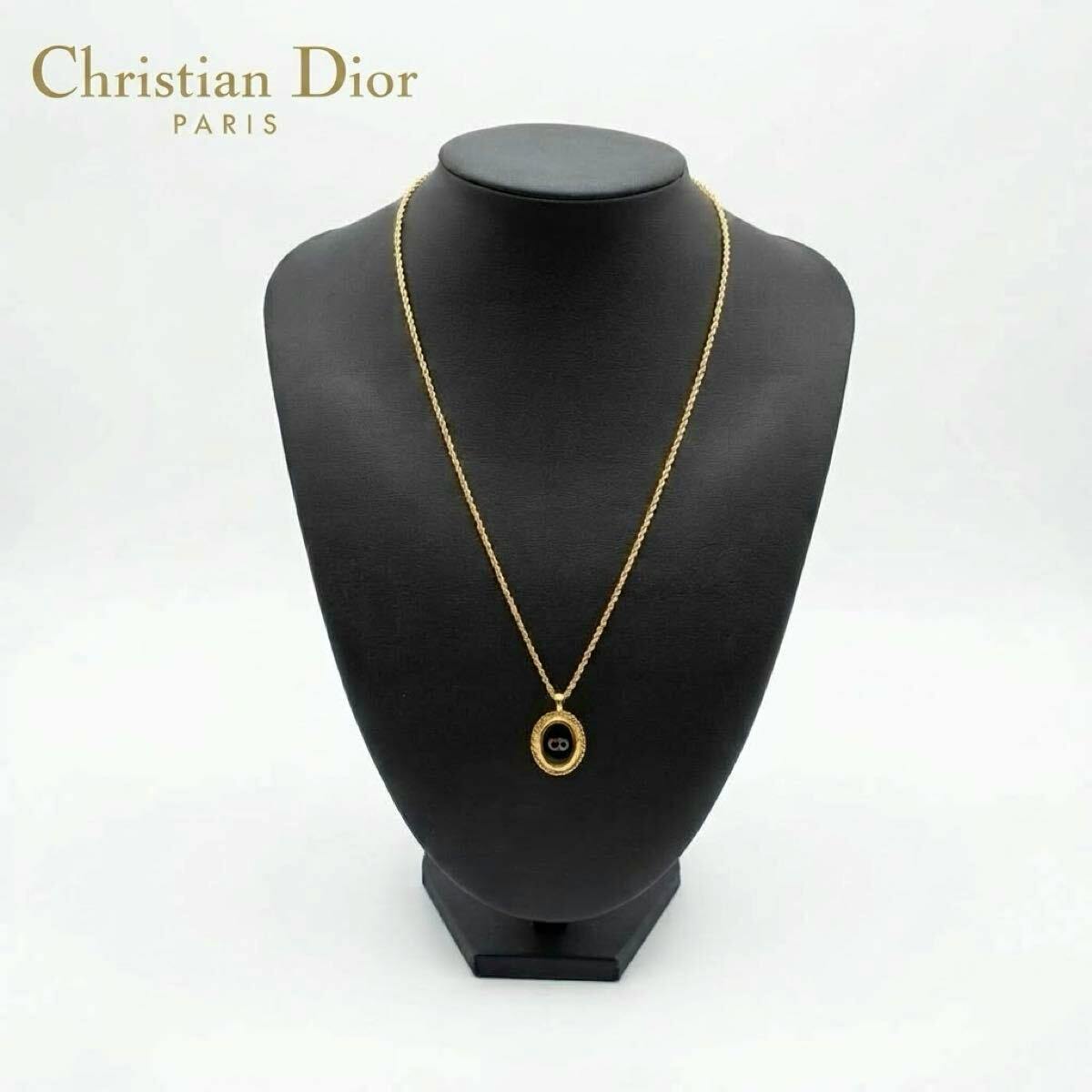 Gold-tone necklace with an oval black CD-logo pendant shown on a black display bust.