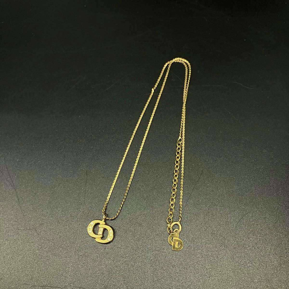 A Christian Dior vintage necklace with a CD logo pendant and rhinestone details laid flat on a black background, showing the chain and clasp.