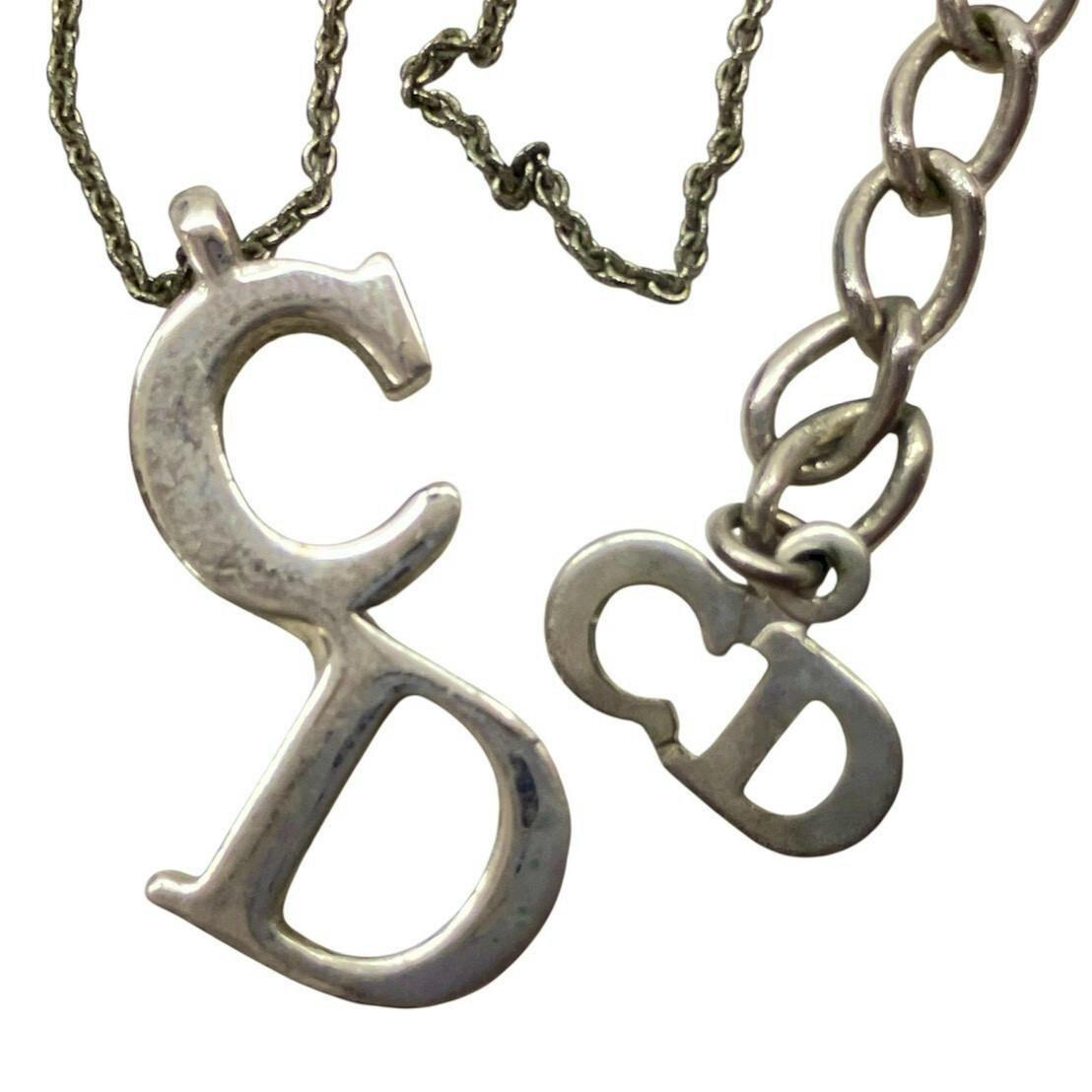 Close-up of a silver-color Christian Dior necklace showing CD logo pendants on a chain.