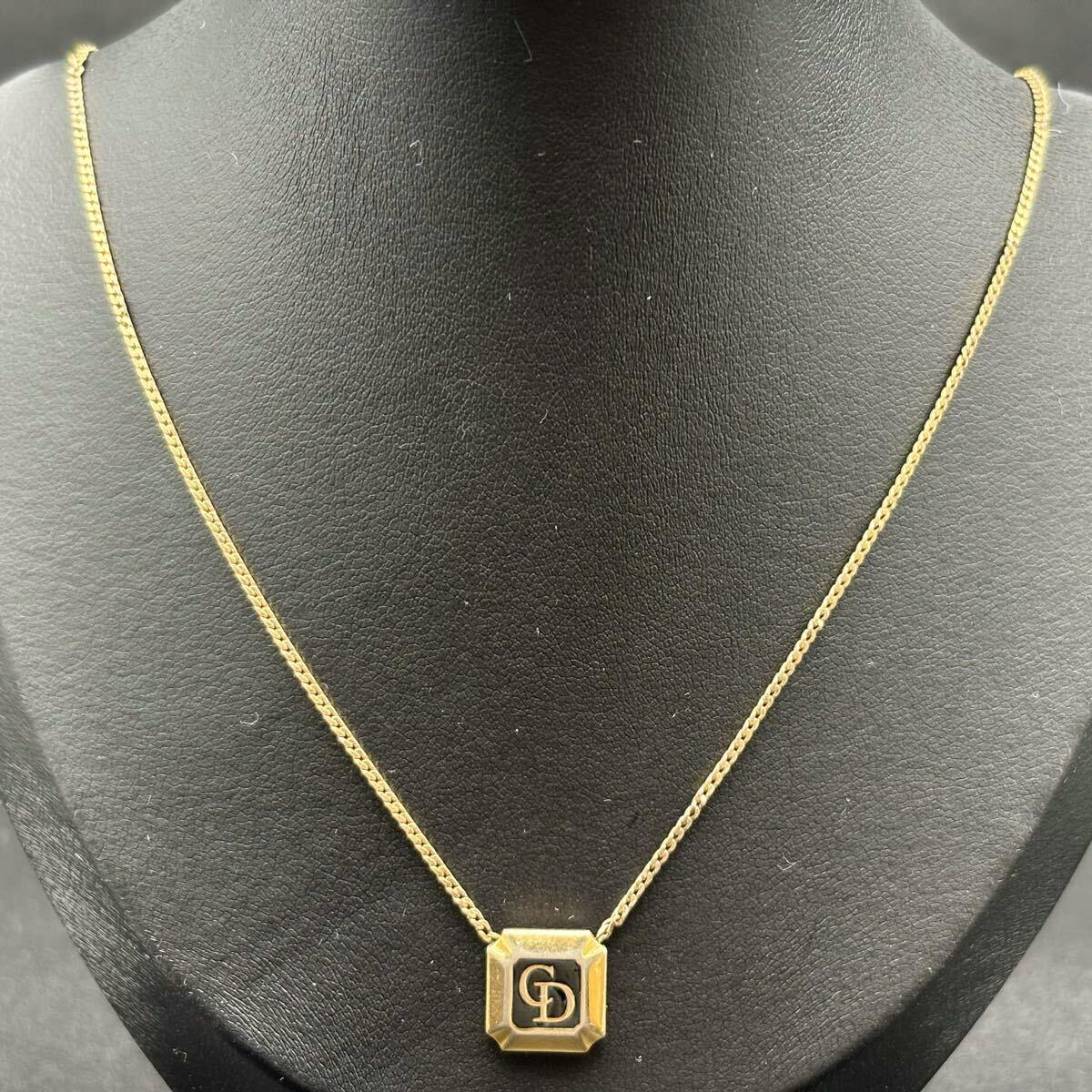 Gold-tone Christian Dior necklace with a square CD logo pendant shown on a black display bust.