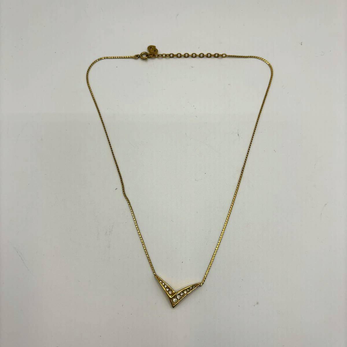 Gold-tone V-shaped pendant necklace with rhinestones on a thin chain laid flat on a white background.