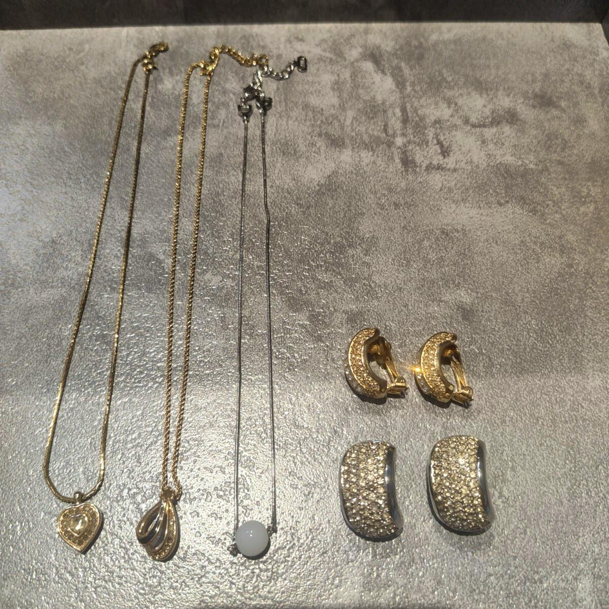 Three necklaces and two pairs of clip-on earrings arranged flat on a gray textured surface.
