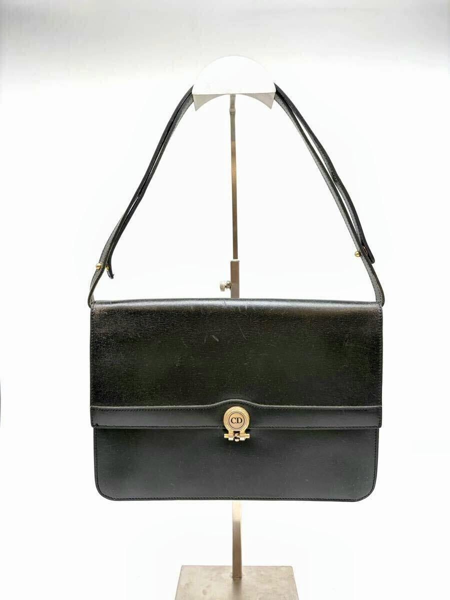 Front view of a black Christian Dior leather shoulder bag with a CD logo clasp displayed on a stand.