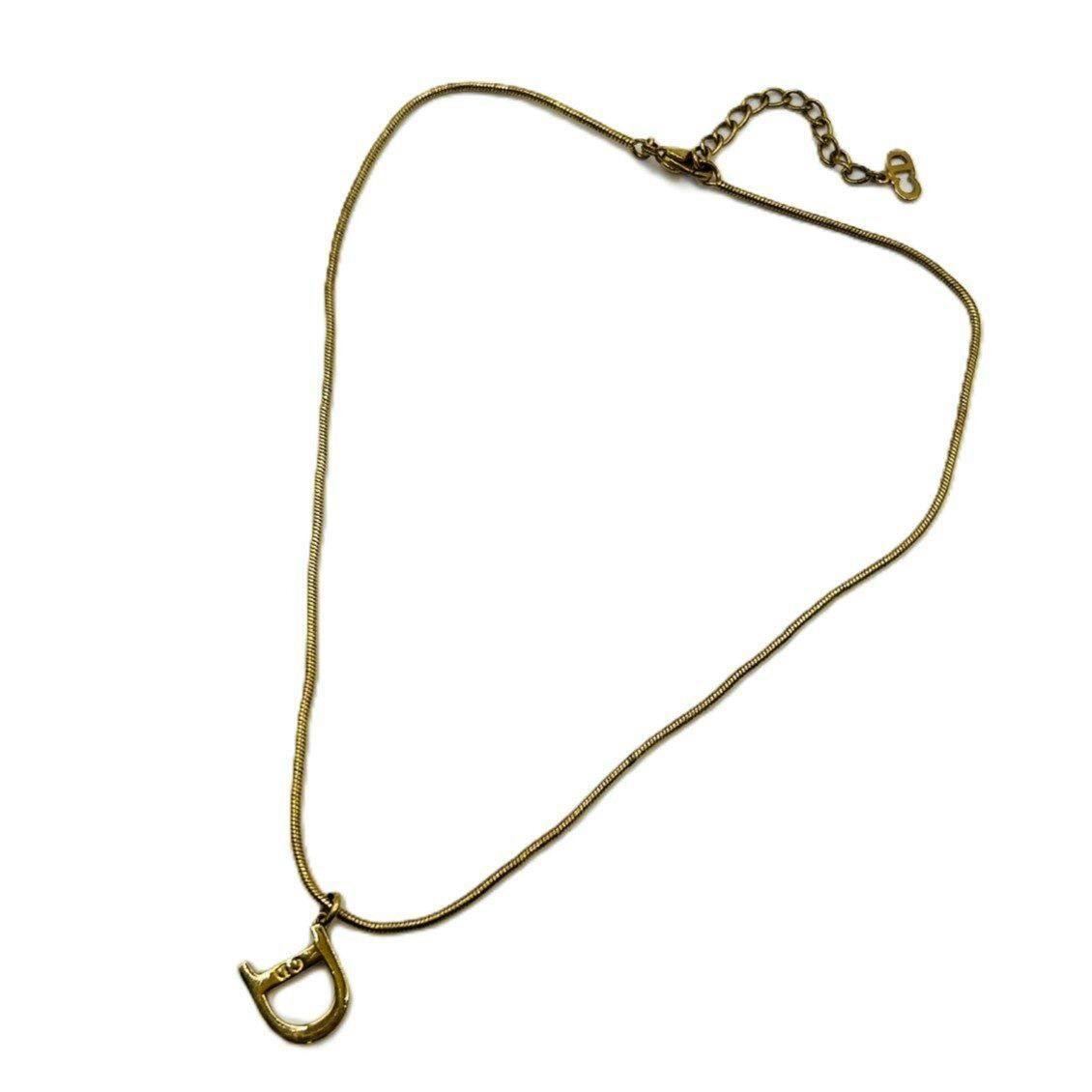 Gold-tone Christian Dior D-logo snake chain necklace with pendant and clasp laid flat on a white background.