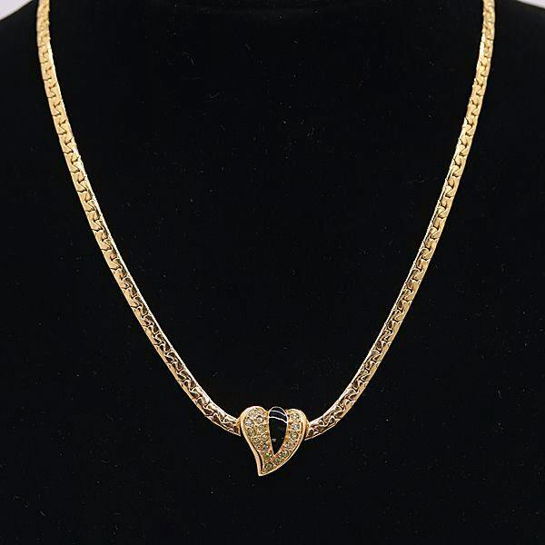 Gold-colored Christian Dior vintage necklace with a heart-shaped pendant shown on a black display.