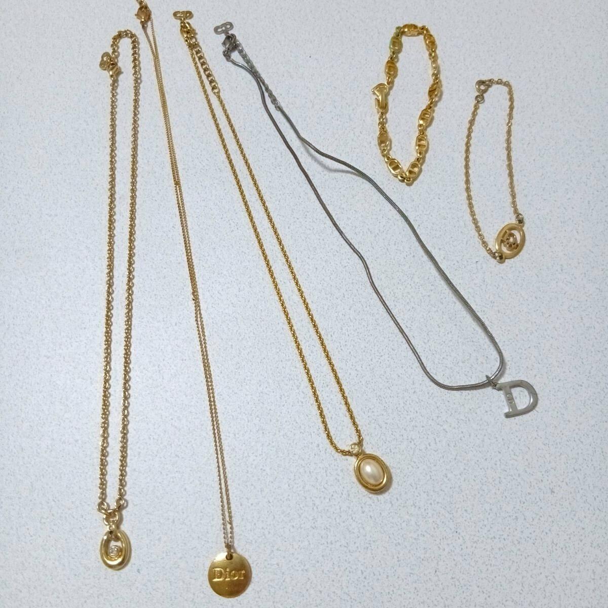 Six Christian Dior necklaces and bracelets laid flat showing gold and silver chains with pendants and charms.