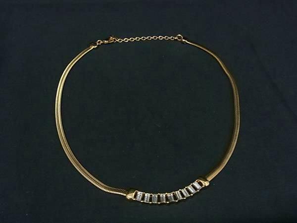 Gold-toned Christian Dior choker-style necklace with a row of rectangular clear stones on a black background.