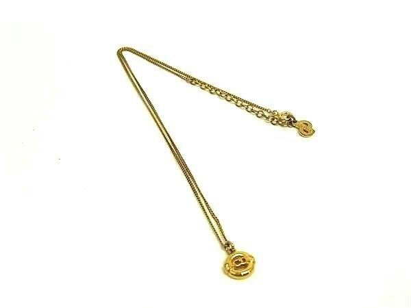 Gold-tone Christian Dior vintage necklace with a small round pendant and extension chain laid flat on a white background.