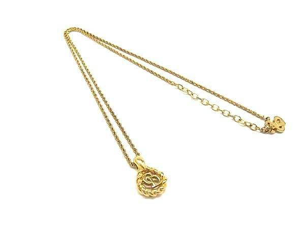 Gold-tone Christian Dior necklace with a braided round pendant featuring interlocking CD letters displayed on a white background.
