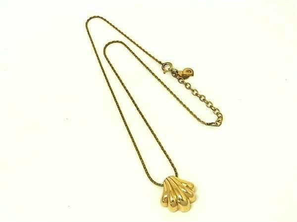 Gold-tone vintage Christian Dior women's necklace with a shell-shaped pendant and chain on a white background.