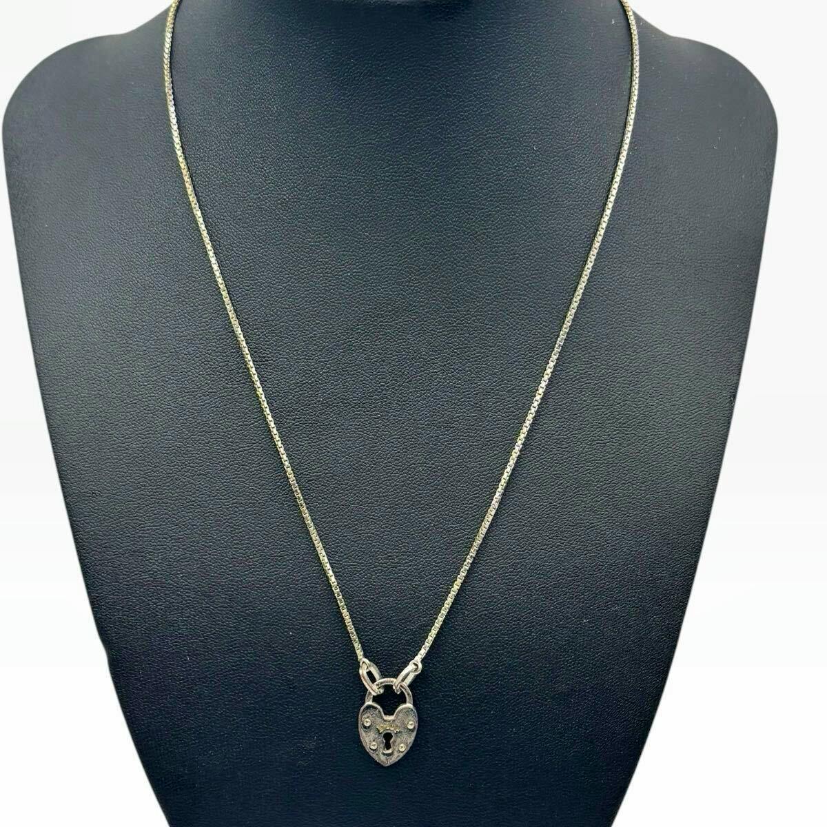 A Christian Dior heart padlock necklace in silver color displayed on a black necklace bust.