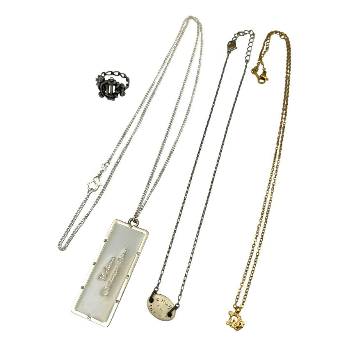 Four Christian Dior necklaces and a ring arranged on a white background, showing pendants and chains.