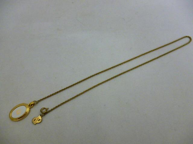 Gold-colored Christian Dior vintage necklace with an oval pendant and rope-style chain laid flat on a white background.