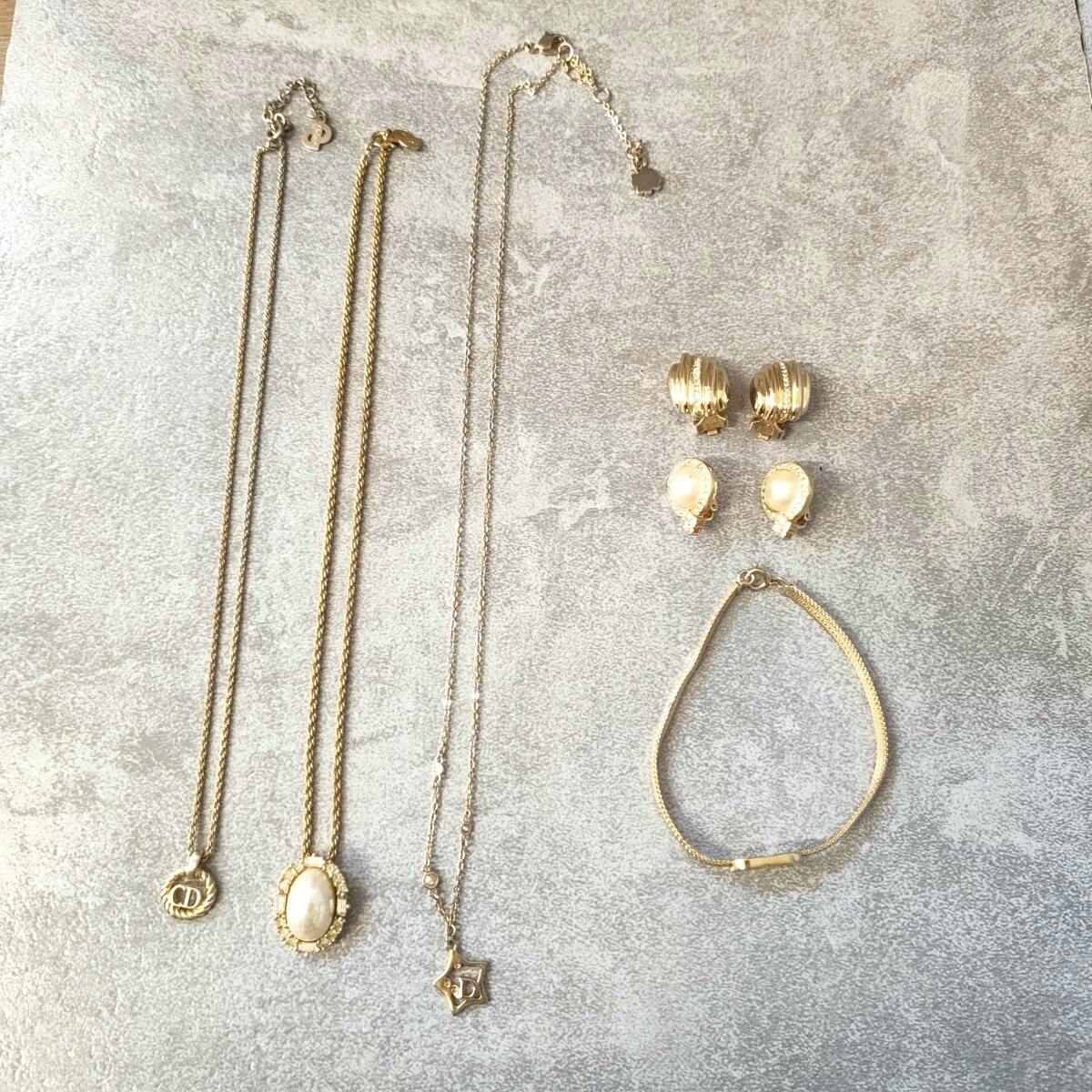 Six-piece Christian Dior jewelry set arranged on a gray background, showing three necklaces, two pairs of earrings, and one bracelet.