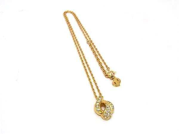 Gold-tone Christian Dior necklace with a linked chain and a rhinestone-studded circular pendant on a white background.