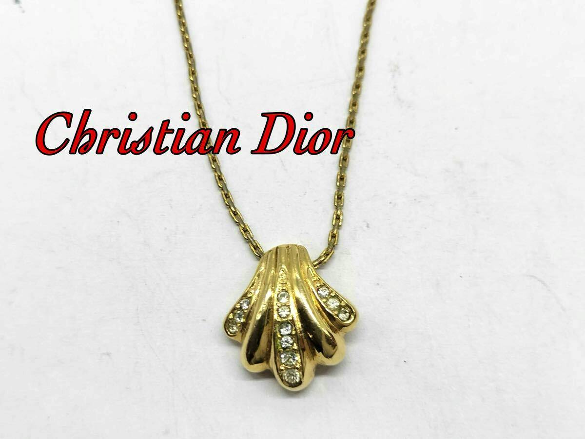 Gold-tone shell-shaped necklace pendant with rhinestone accents and its chain on a white background.