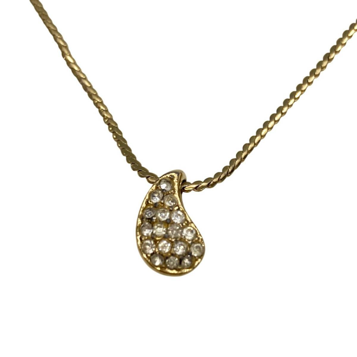 Close-up of a gold-tone Christian Dior teardrop pendant necklace with multiple rhinestones on a gold chain.