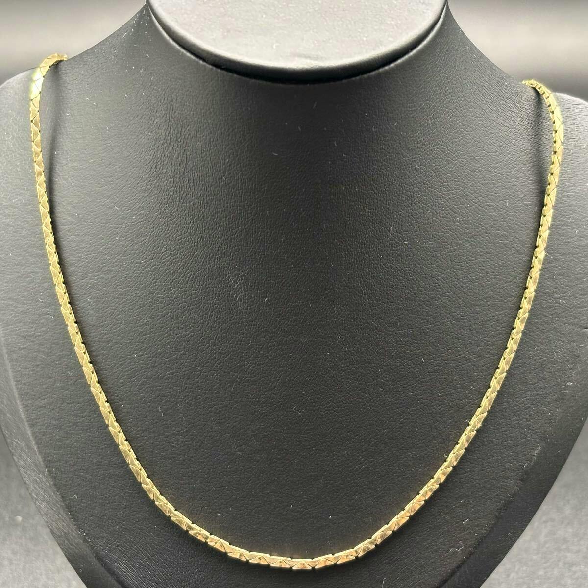 Gold triangular-link necklace displayed on a black jewelry bust.