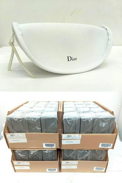 White Dior zippered sunglasses pouch with the 'Dior' logo visible on the front, shown above stacked boxed sets.