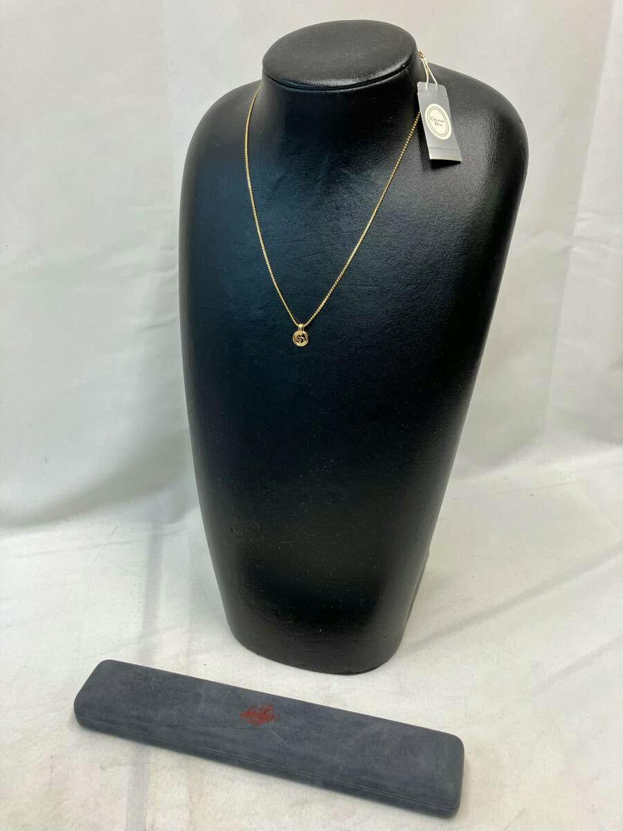 Gold Christian Dior plated necklace with a small round pendant displayed on a black necklace bust with its tag.
