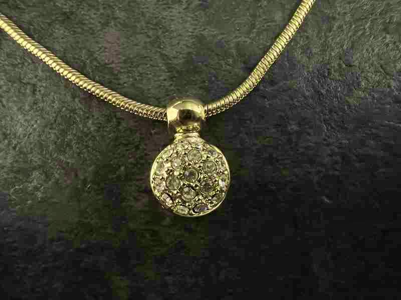 Close-up of the Christian Dior women's necklace showing a round crystal-encrusted pendant on a snake chain.