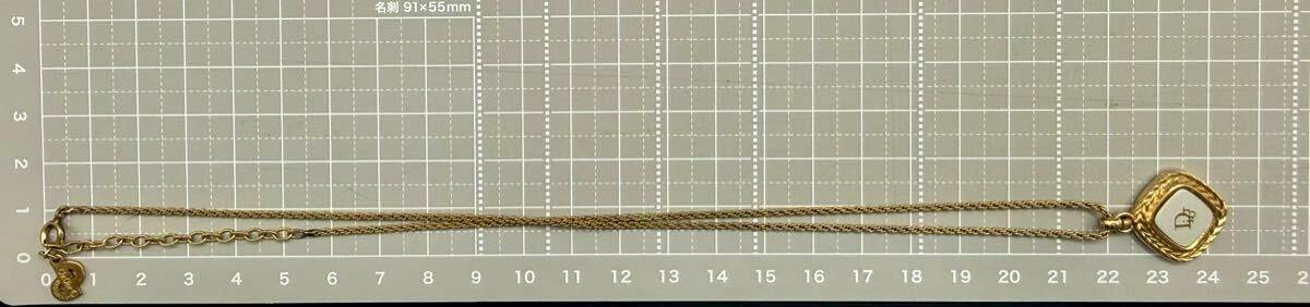 Full-length photo of the Christian Dior necklace with pendant and chain laid flat on a measurement grid.