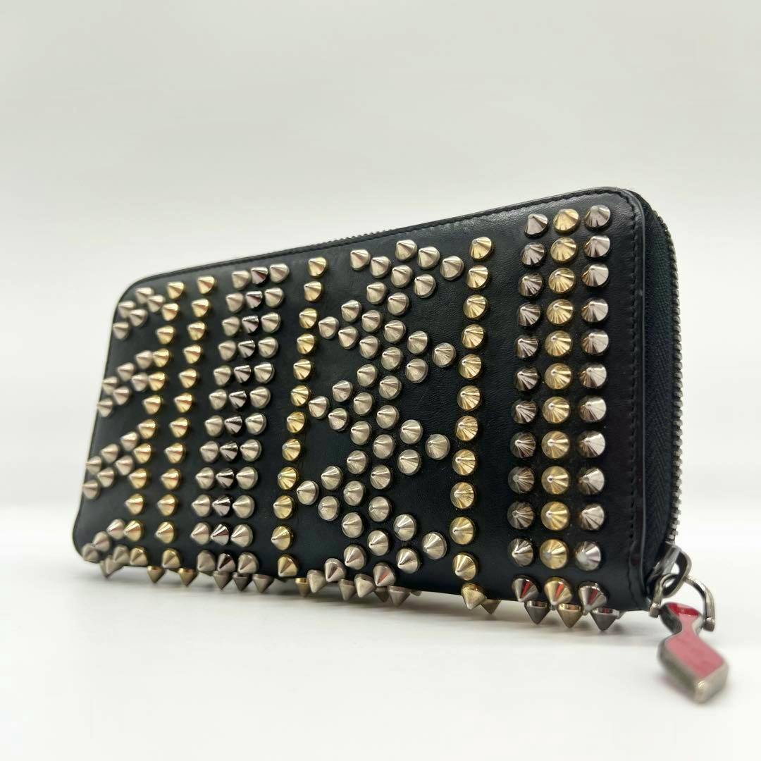Black leather long zip-around wallet studded with gold and silver spikes and a red-accented zipper pull.