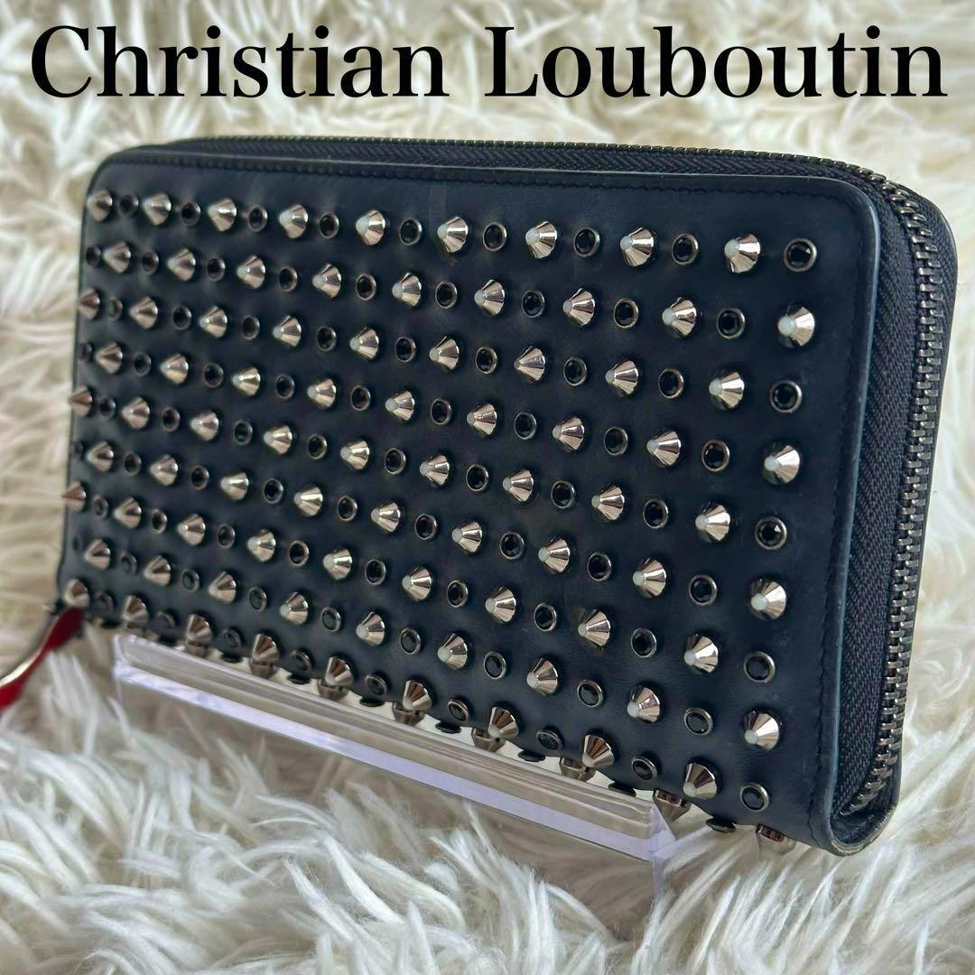 Black cow-leather long zip-around wallet with multiple metal studs, shown at an angle on a light textured background.