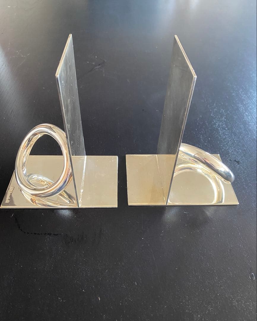 Photo of two silver Christofle bookends with vertical plates and circular ring elements placed on a dark surface.