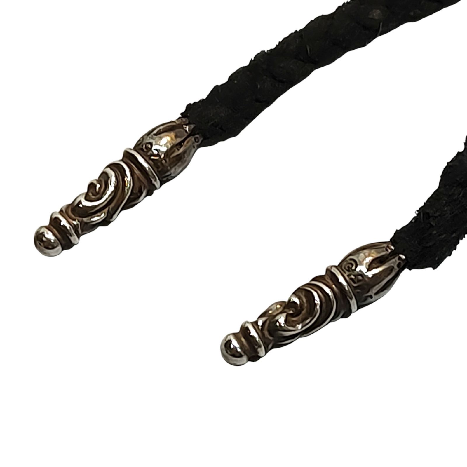 Close-up of a black braided cow leather bag strap showing decorative metal scroll end caps.